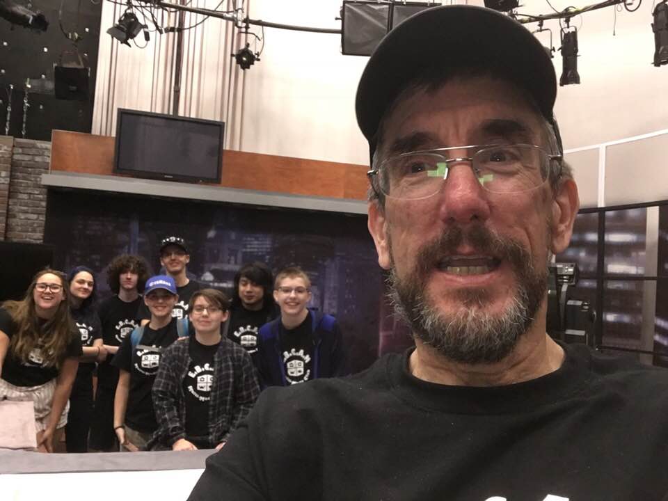 Man with beard smiling with group of teens.